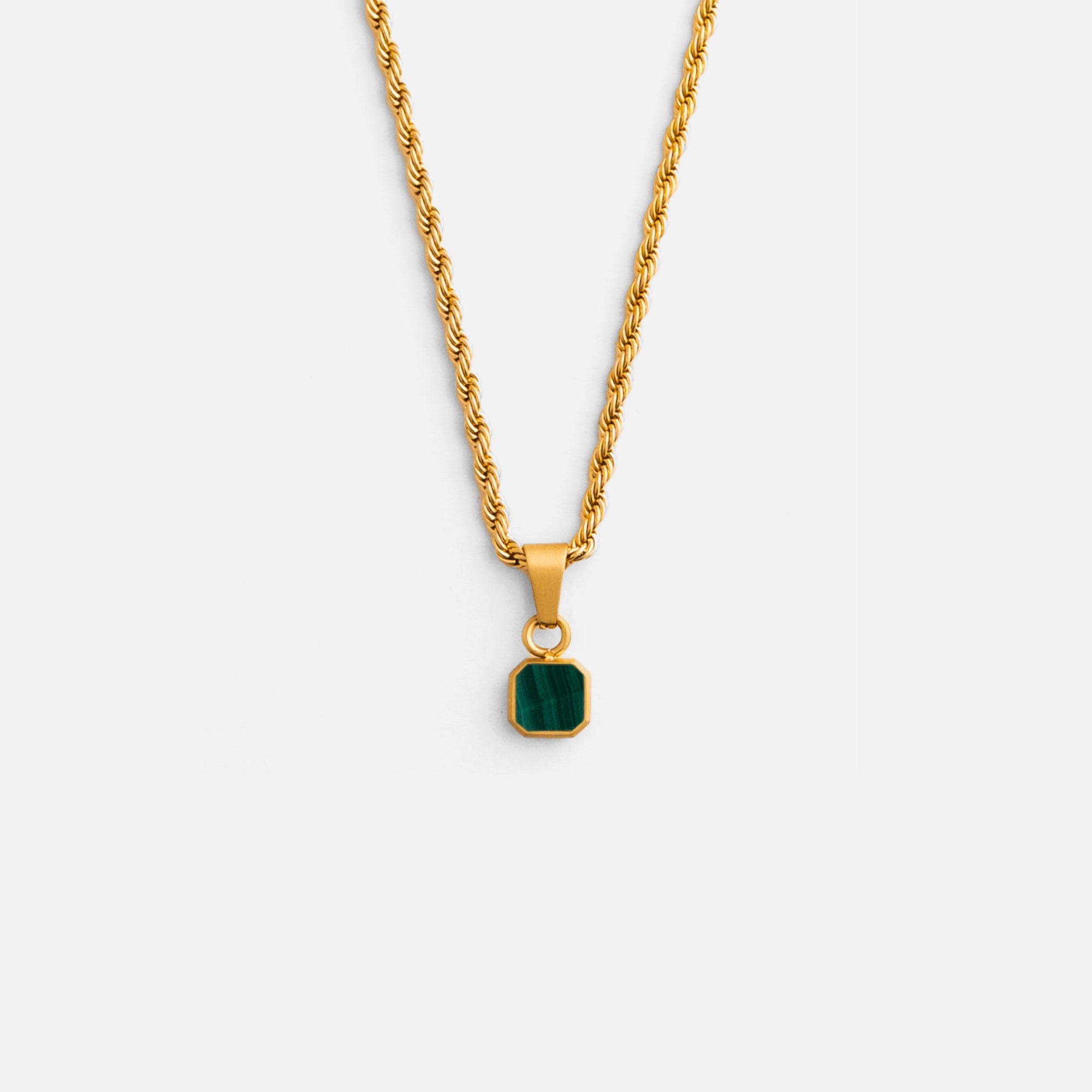 Gold necklace with a green pendant on a white background
