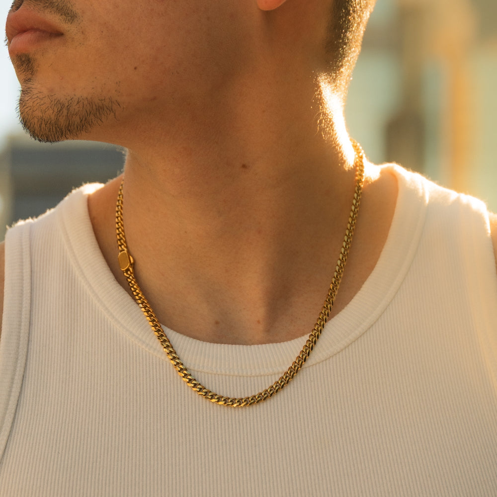 Close-up of a person wearing a gold chain necklace with a blurred background