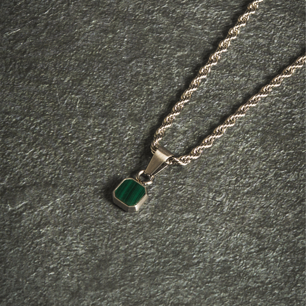 Necklace with a green pendant on a dark gray textured surface