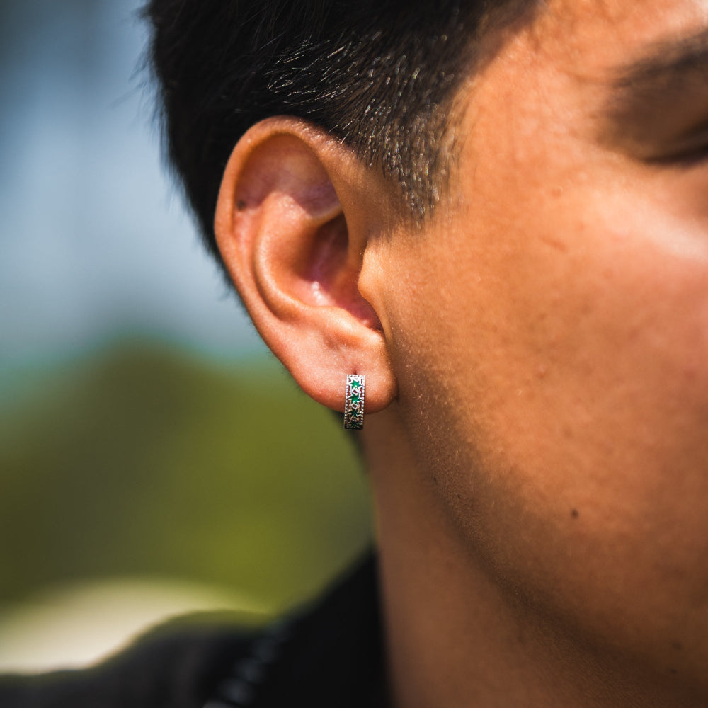 Close-up of a person wearing a small hoop earring with a blurred natural background