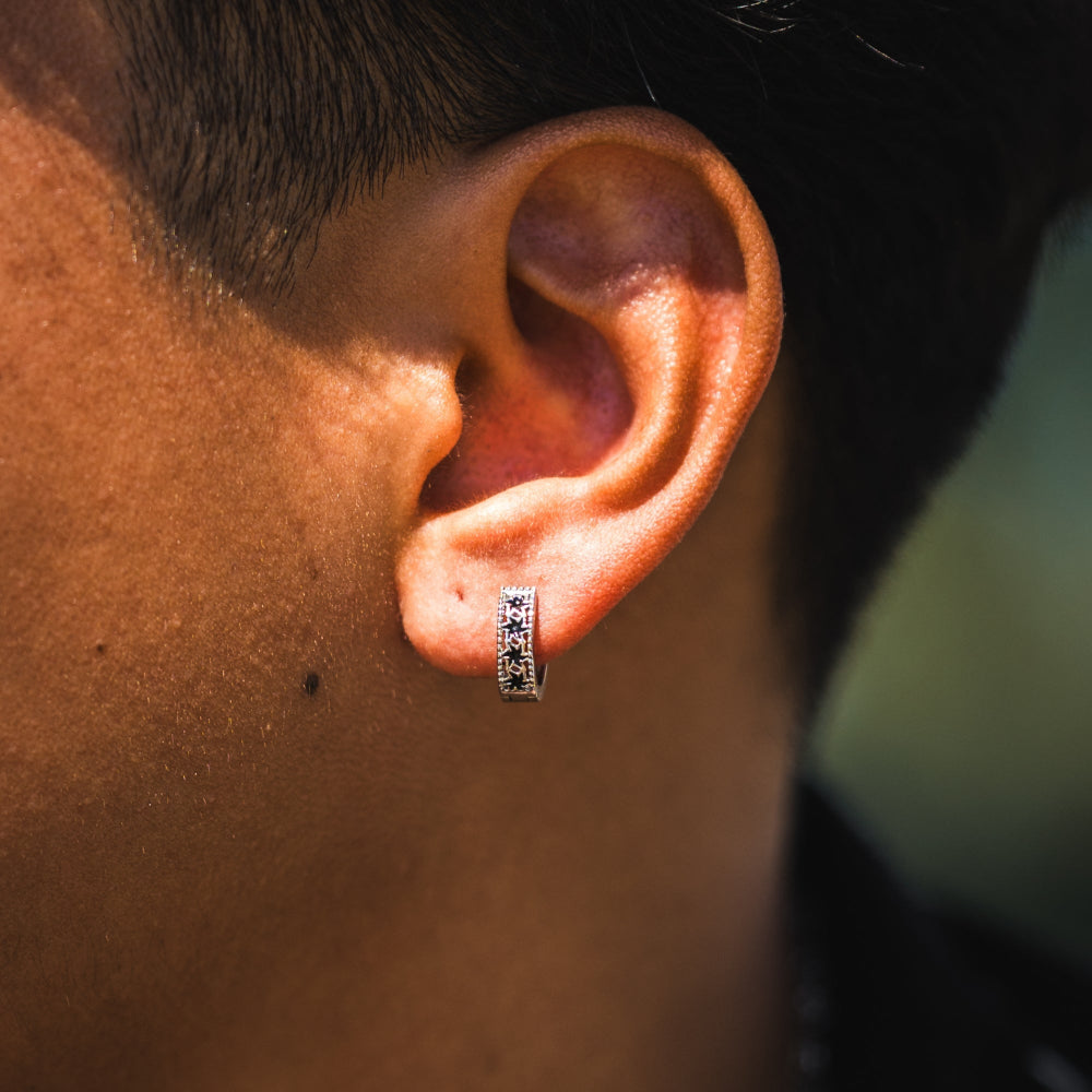 Close-up of an ear with a silver earring against a blurred background