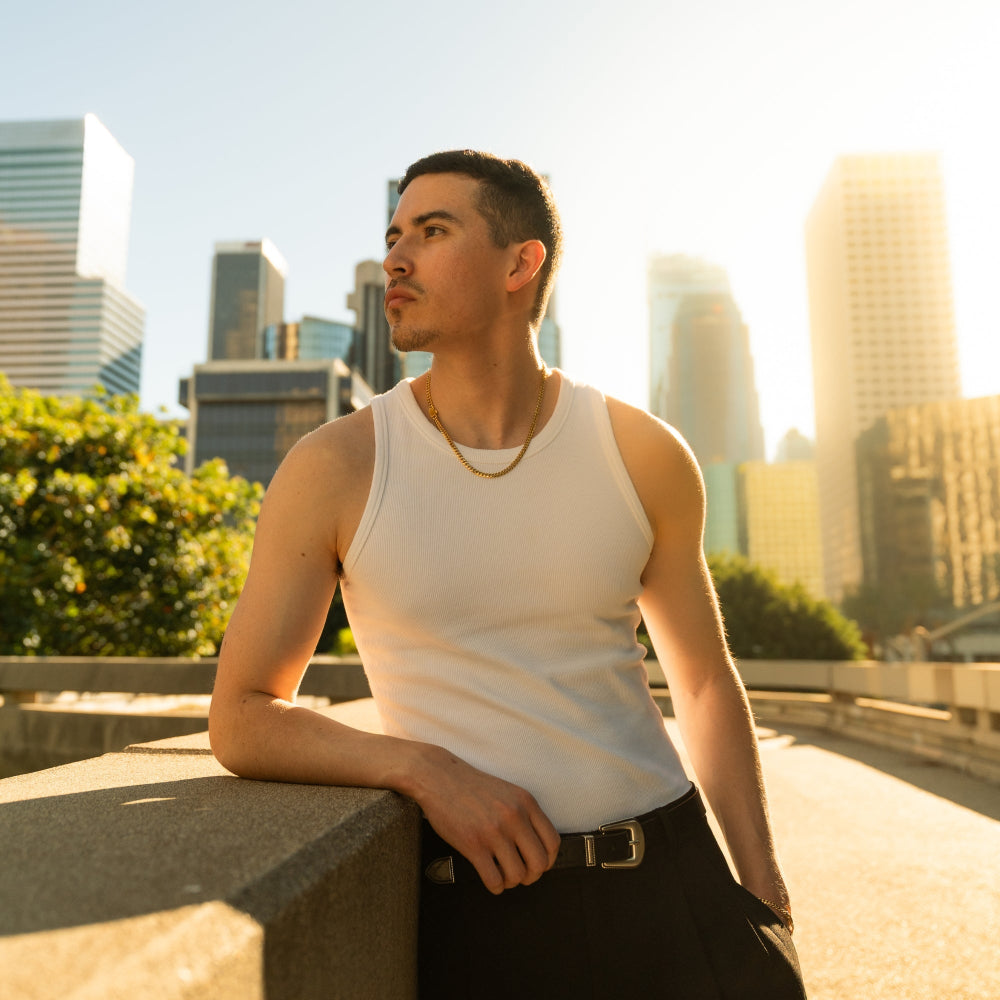 Man in a white tank top standing against a city skyline