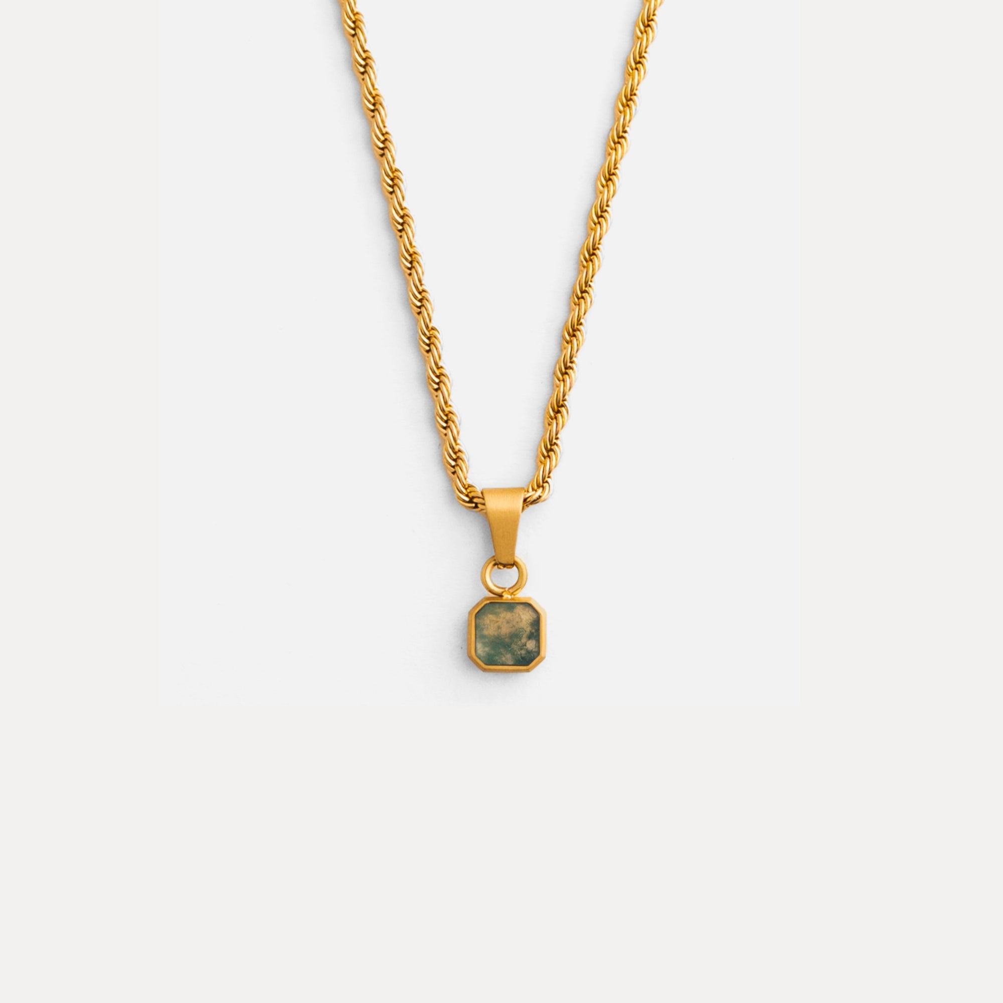 Gold necklace with a square pendant on a light gray background