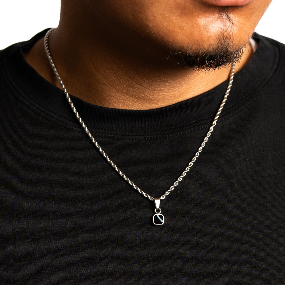 Silver necklace with a pendant on a person wearing a black shirt.