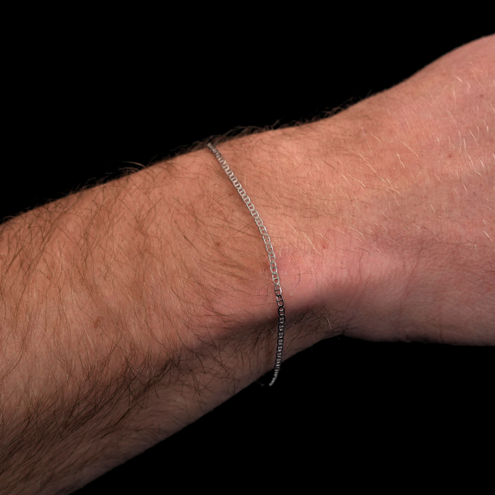 Silver bracelet on a person's wrist against a black background