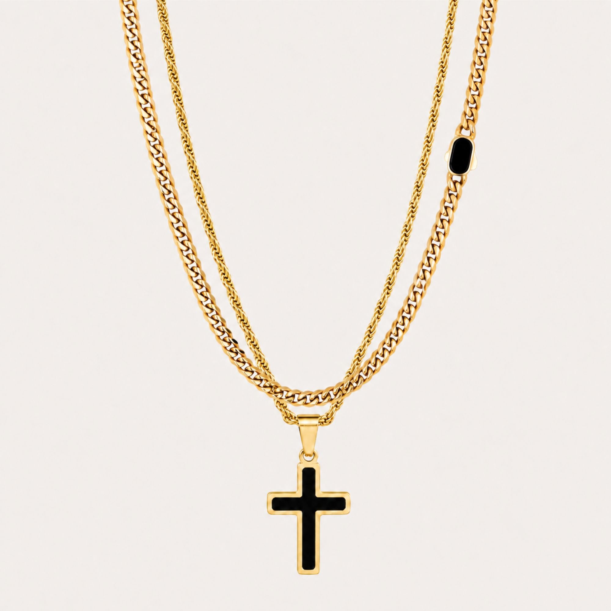 A double-strand gold chain necklace set featuring a classic curb chain and a rope chain with a black enamel cross pendant, displayed on a light beige background.