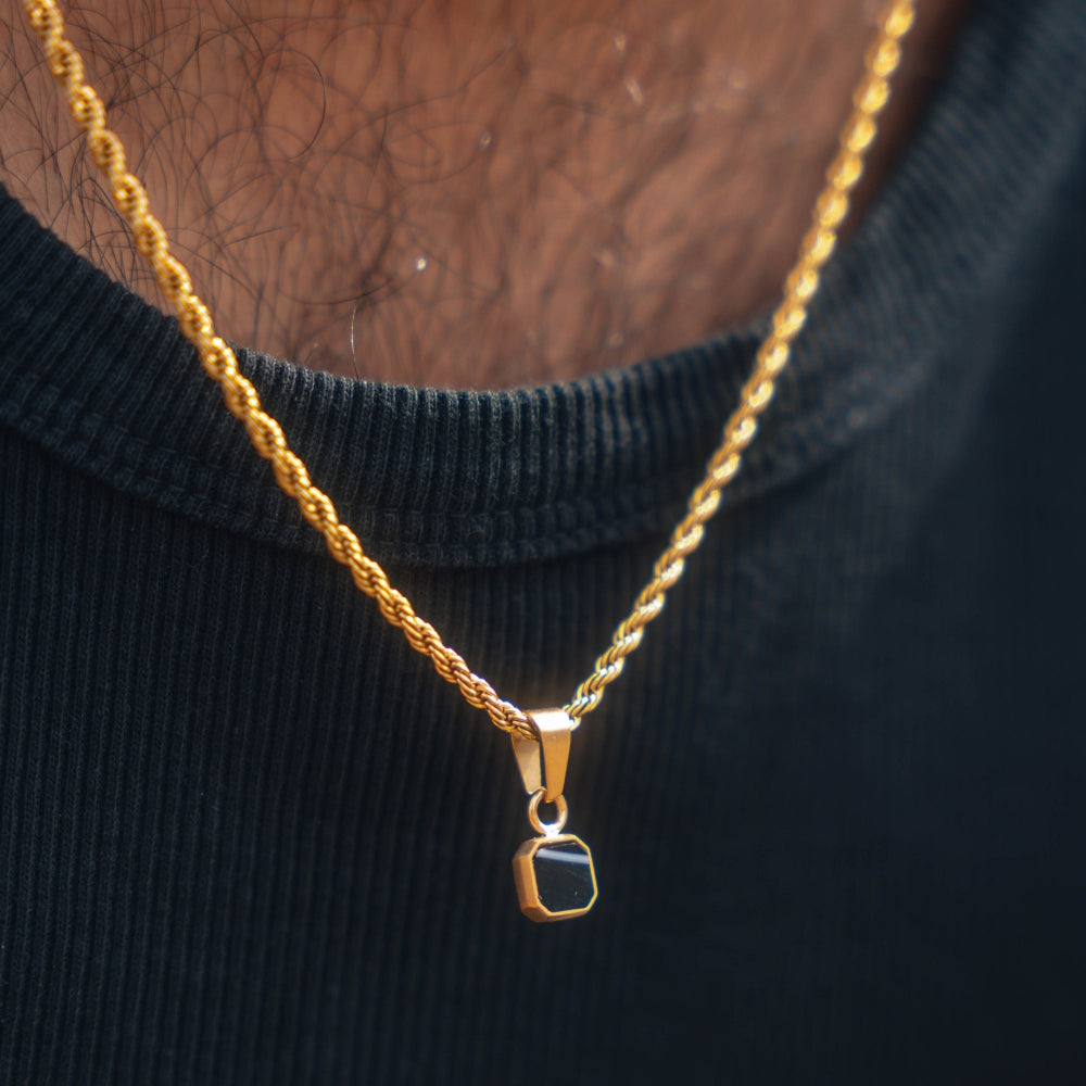 Gold necklace with a pendant on a black background
