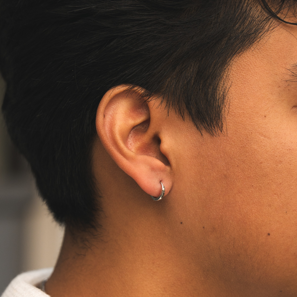 Close-up of a person's ear with a hoop earring, blurred background