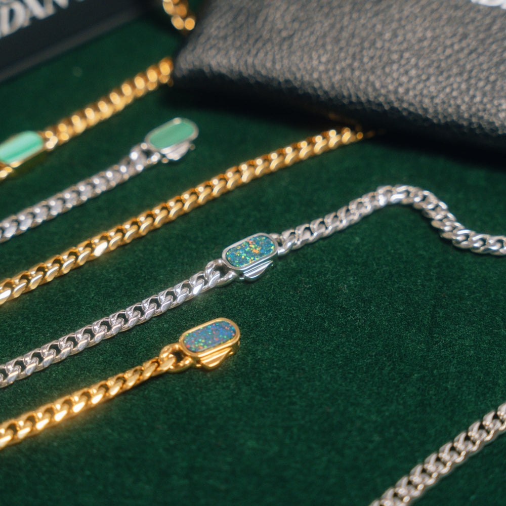 Three bracelets in gold, silver, and a combination of gold and silver on a green surface.