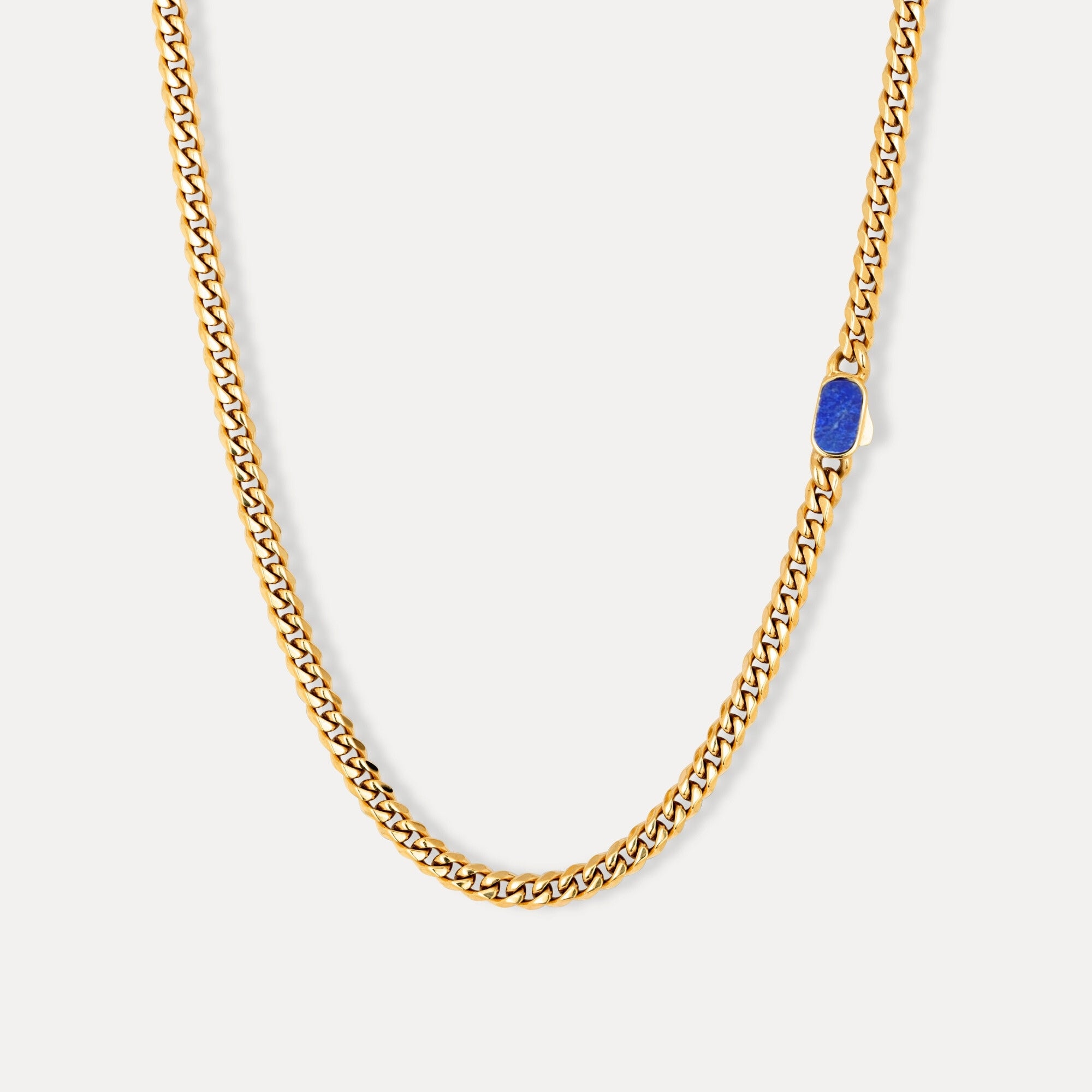 Gold chain necklace with a blue gemstone on a white background