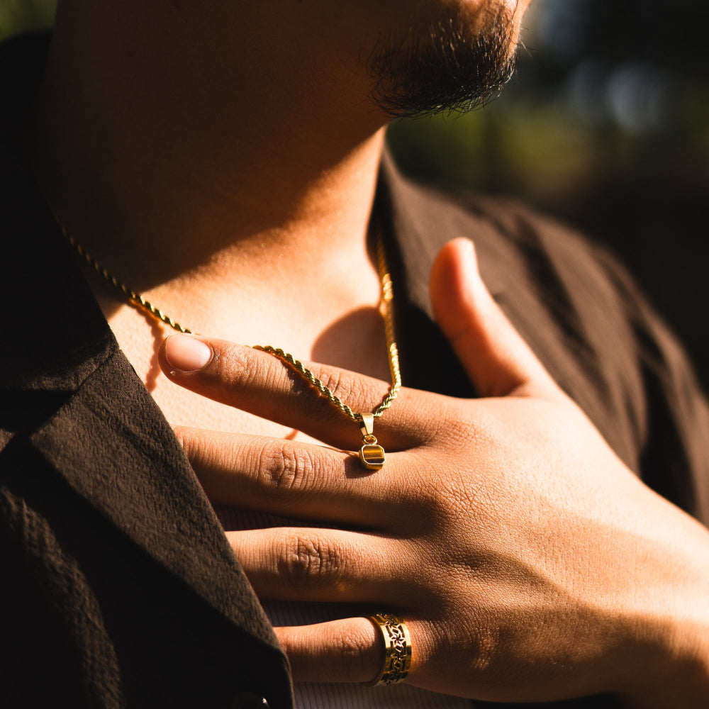 Person wearing a gold necklace and ring with a blurred background