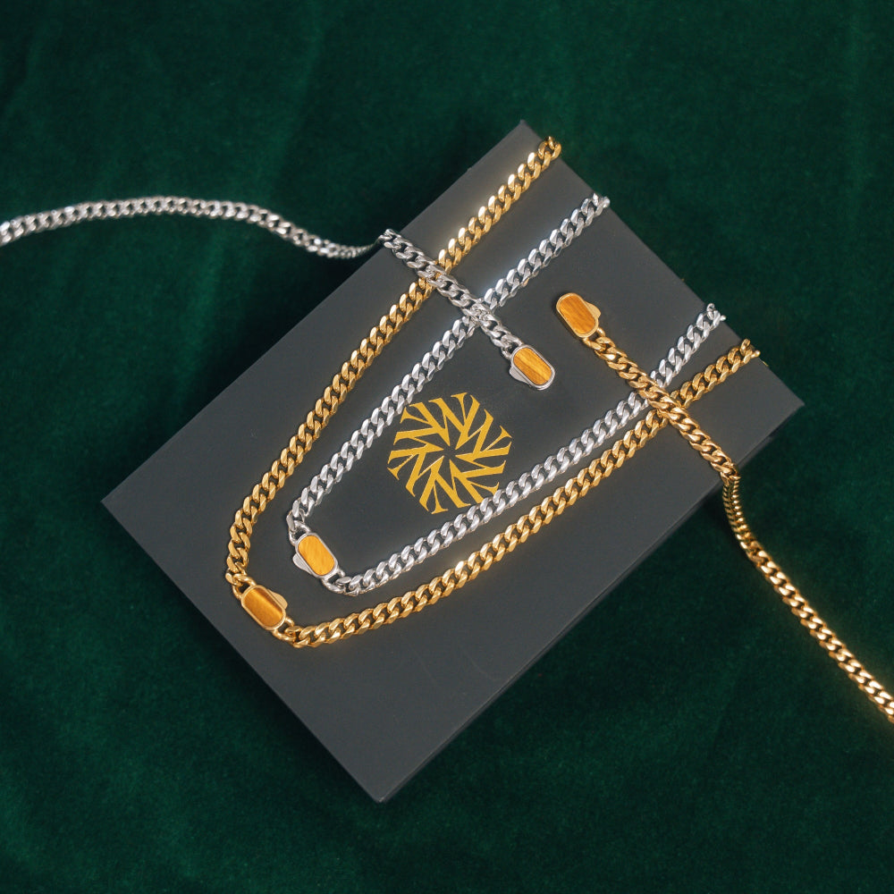 Gold and silver chain necklaces on a dark gray card with a gold emblem against a green background