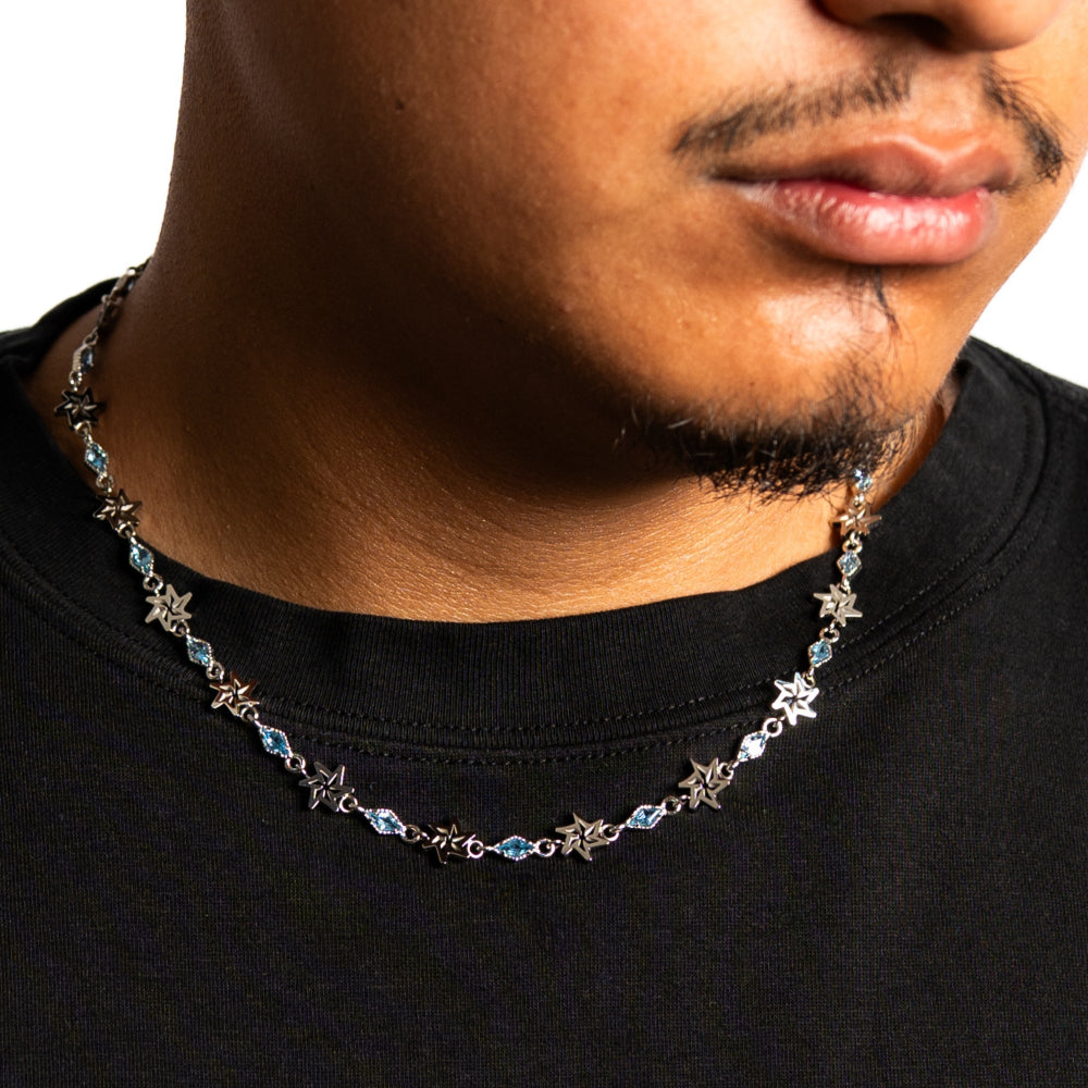 Close-up of a person wearing a star-shaped necklace on a plain background