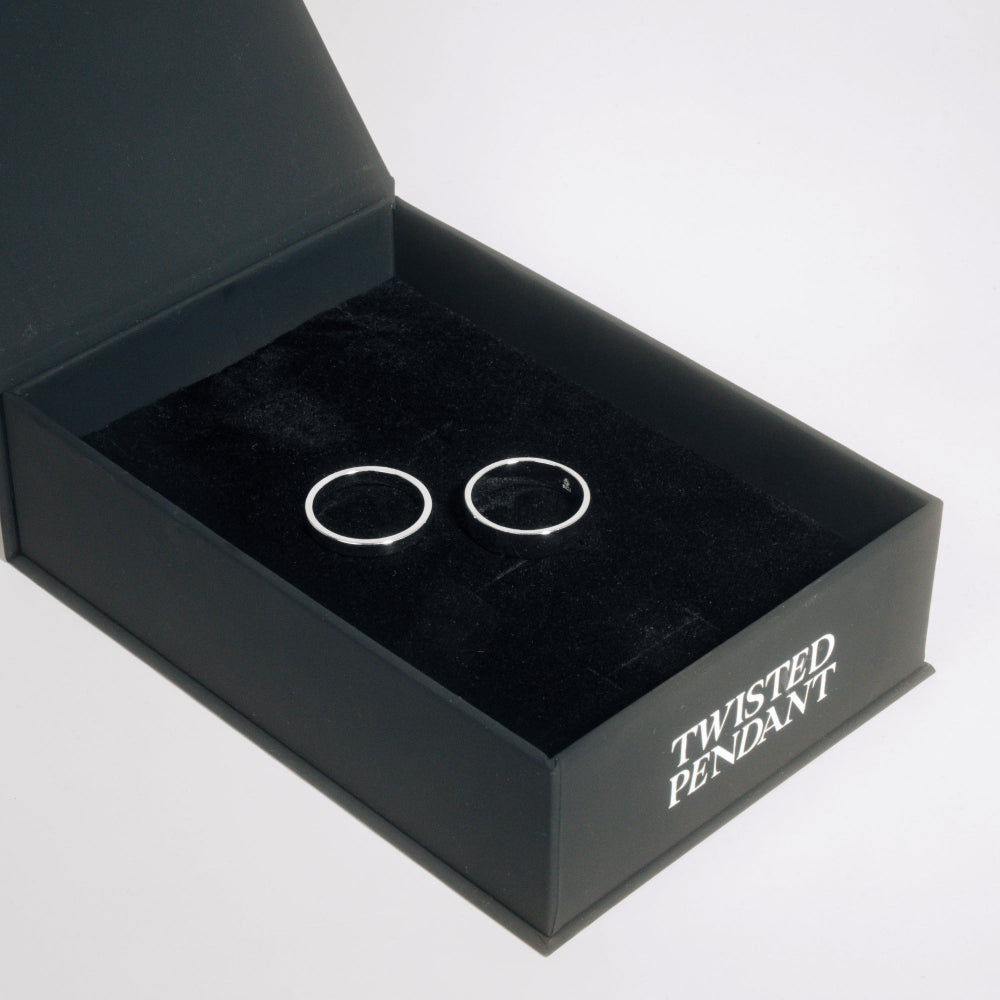 Two silver rings in a black jewelry box labeled 'Twisted Pendant' on a white background