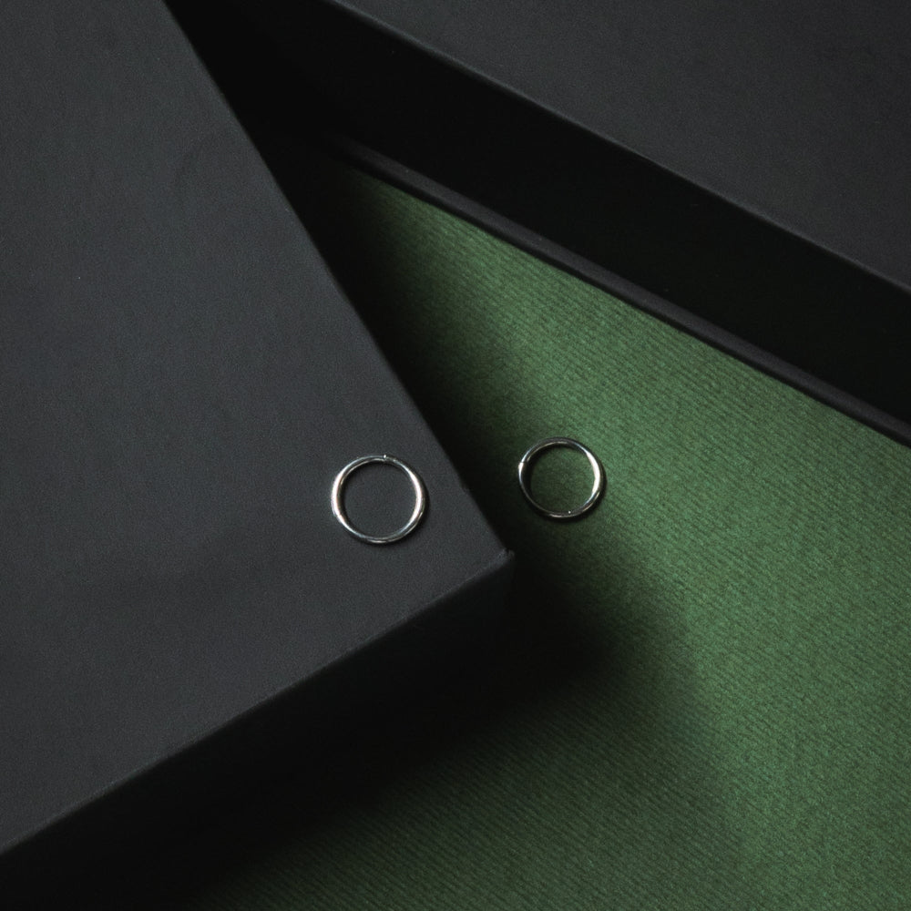 Two silver rings on a dark green surface with a black background