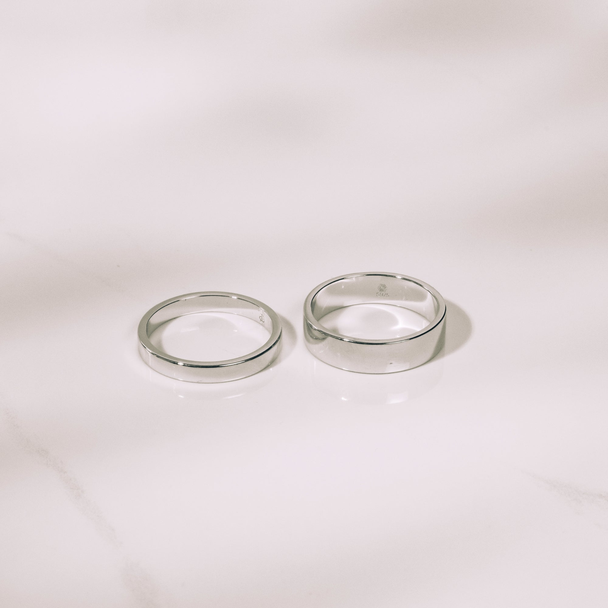 Two silver rings on a light beige background