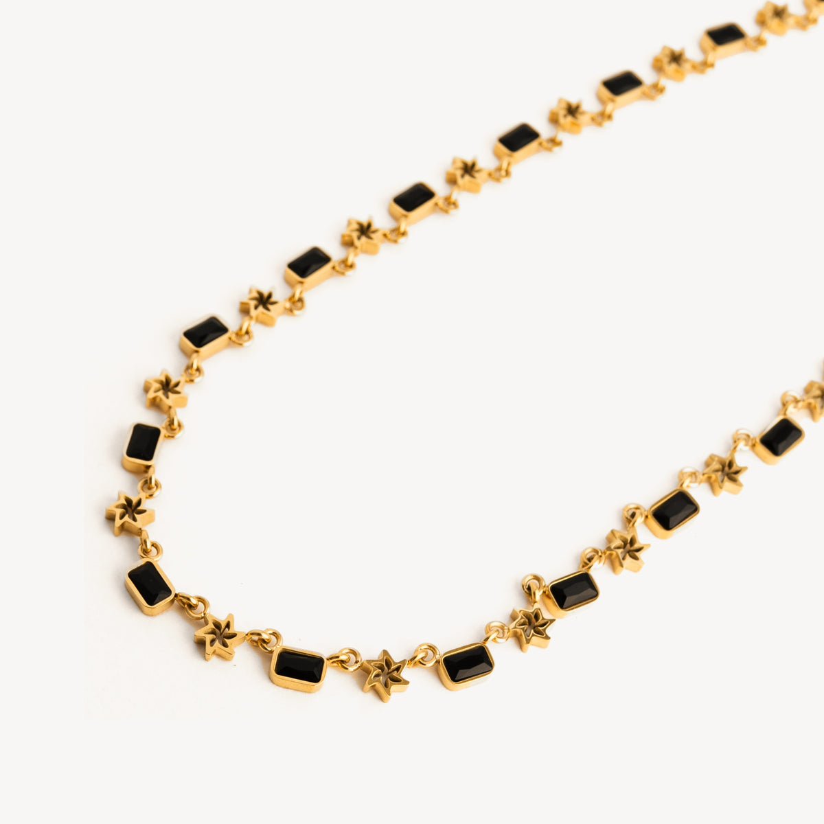Gold necklace with black stones on a white background
