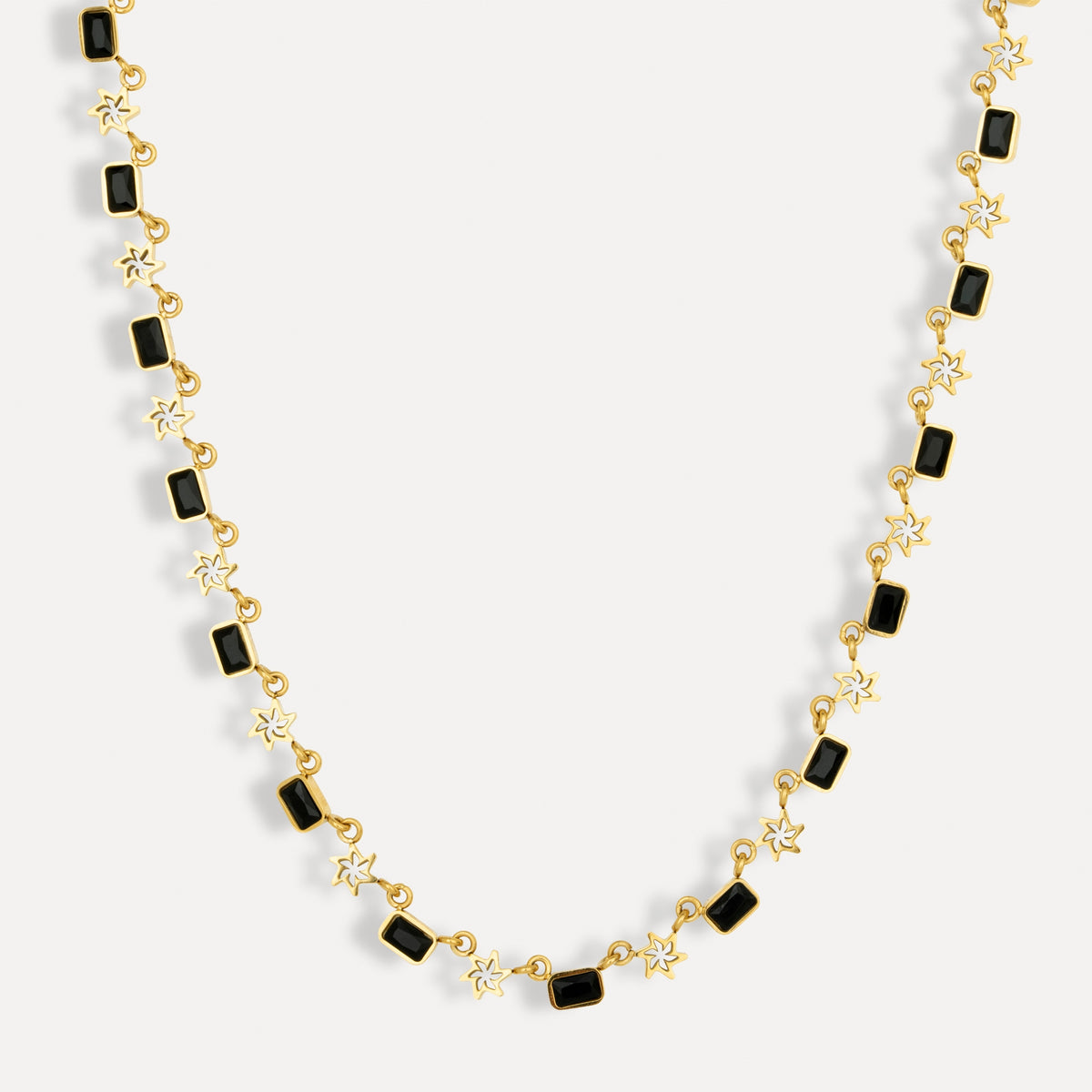 Gold necklace with black square beads on a white background