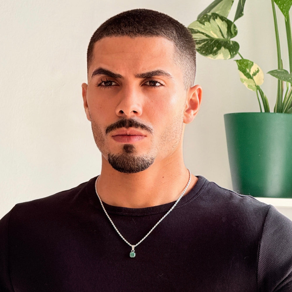Man wearing a black shirt with a plant in the background