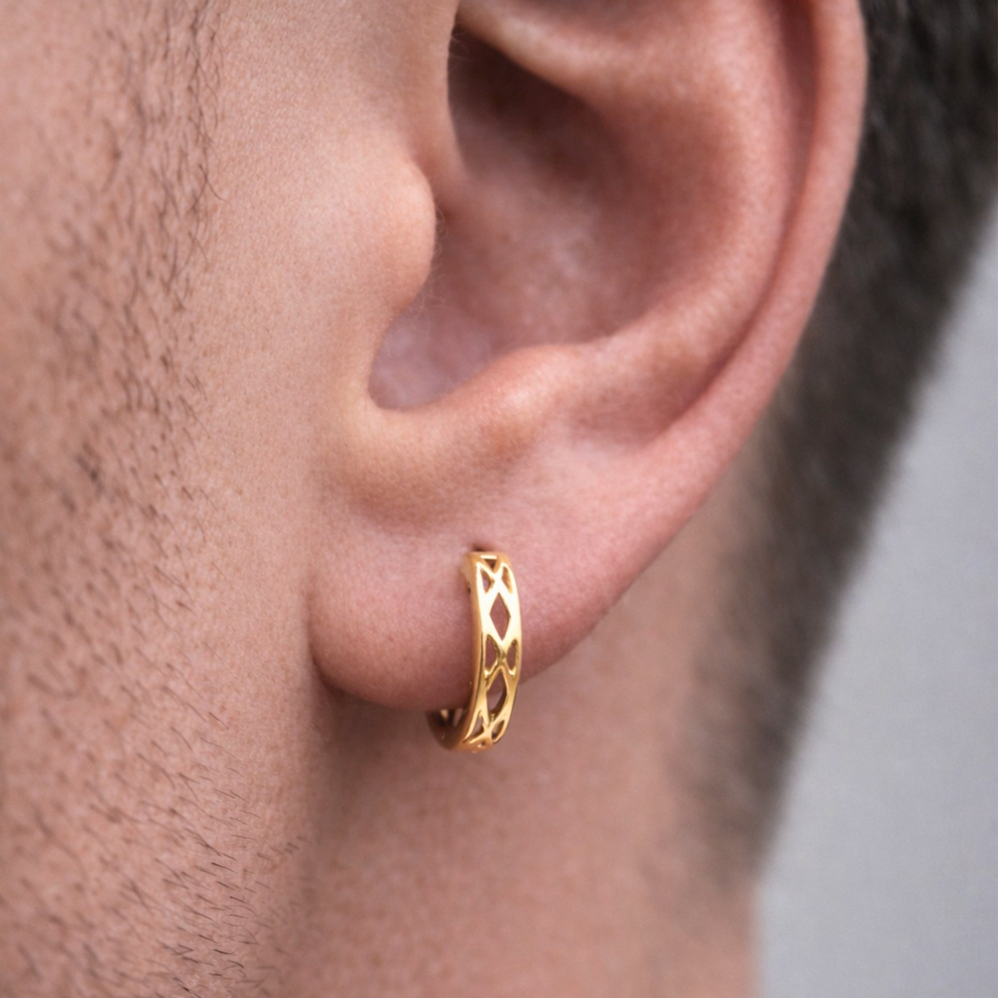 Gold hoop earring worn by a person with a neutral background