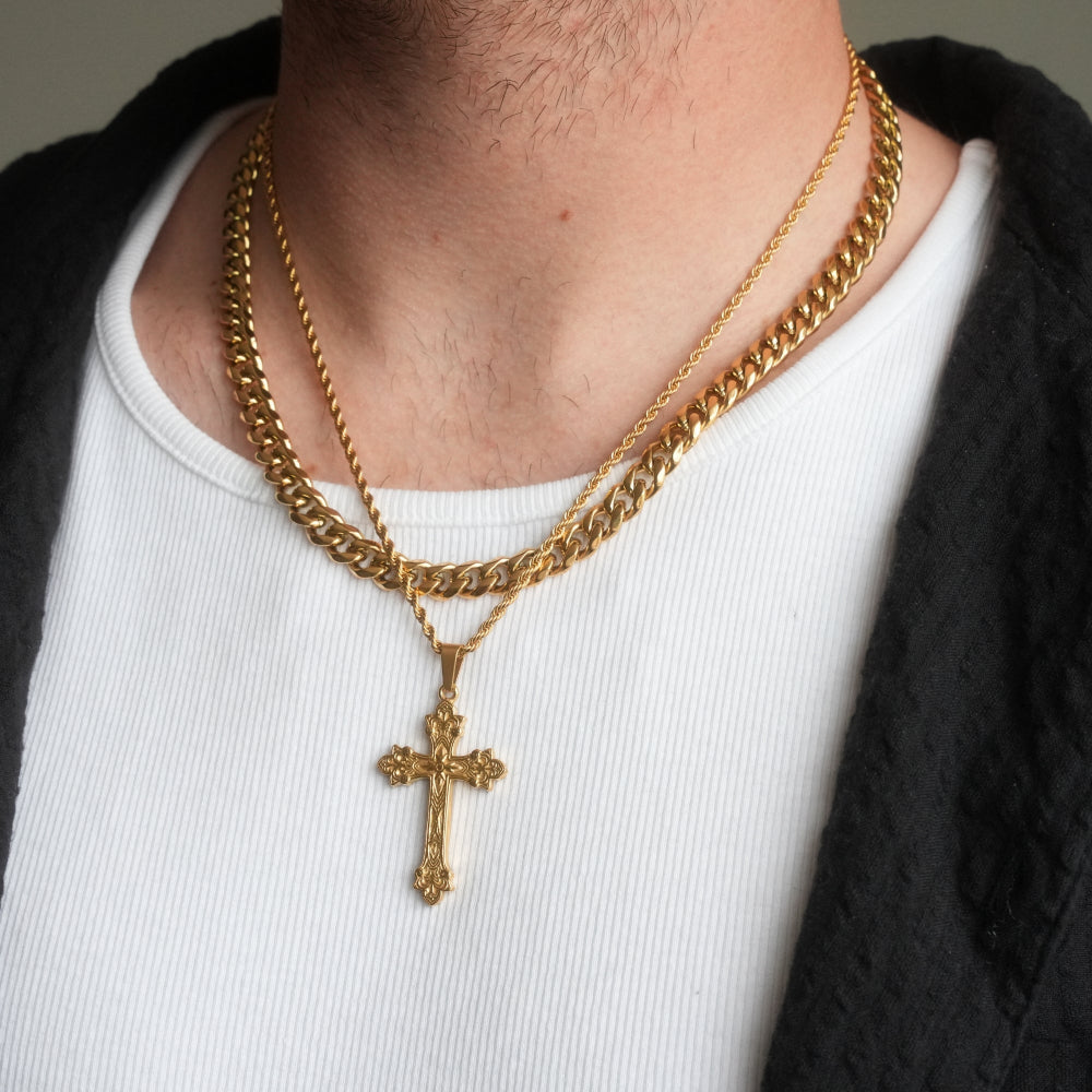 Gold chain necklace with a cross pendant worn by a person on a neutral background