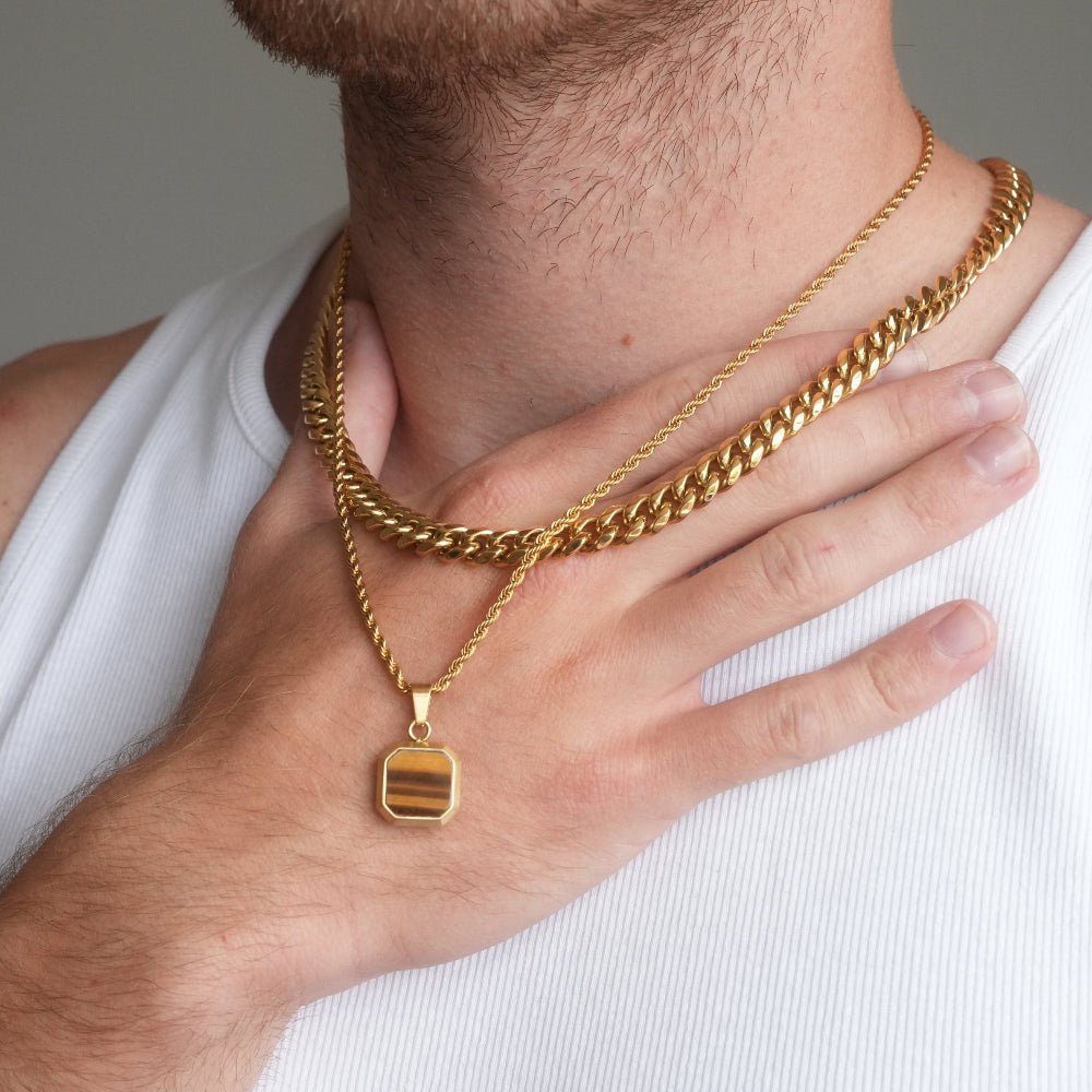 Gold chain necklace with a pendant worn by a person on a plain background