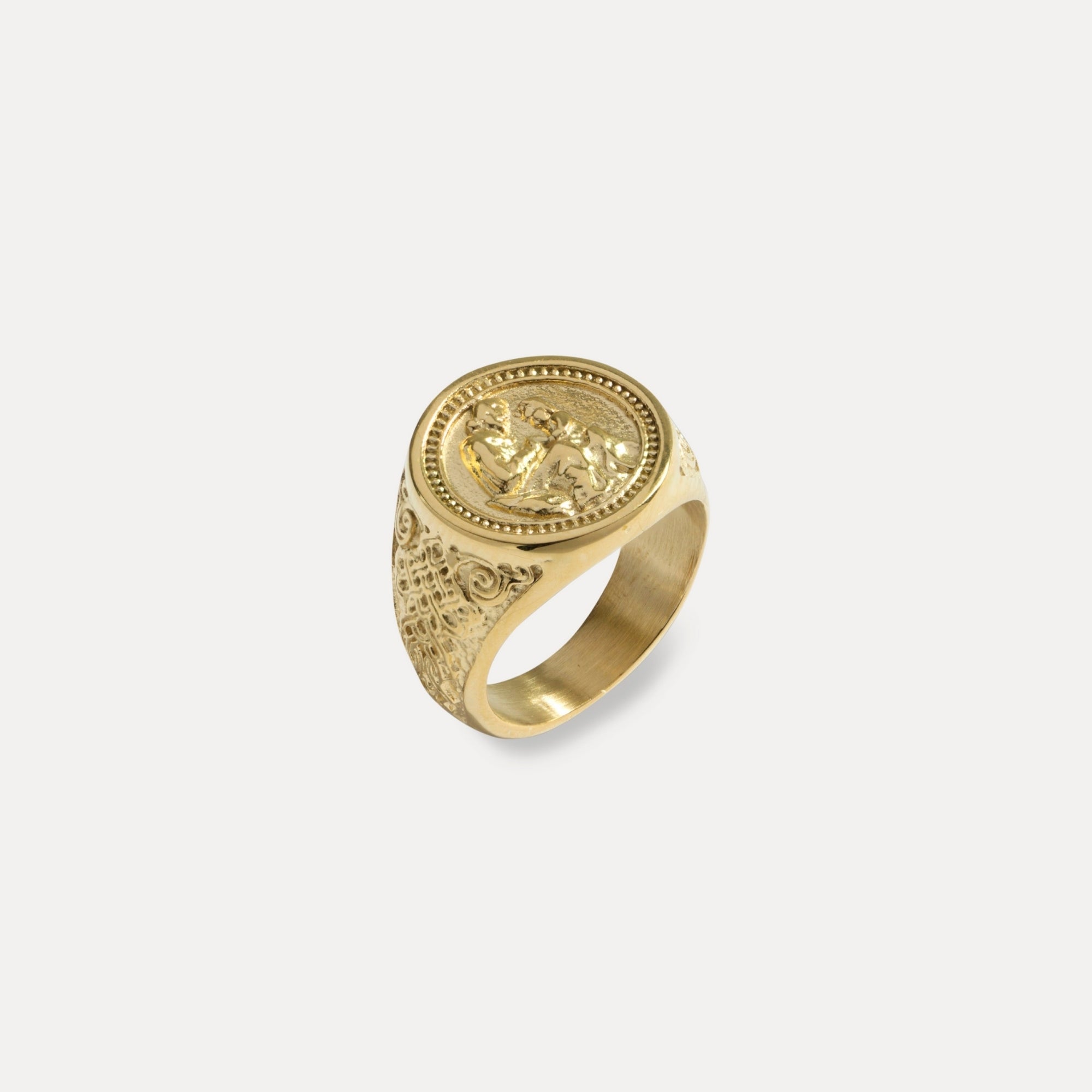 Gold ring with intricate design on a light gray background