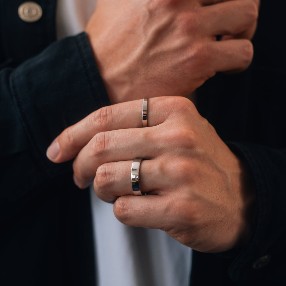Close-up of two hands wearing silver rings with a blurred background