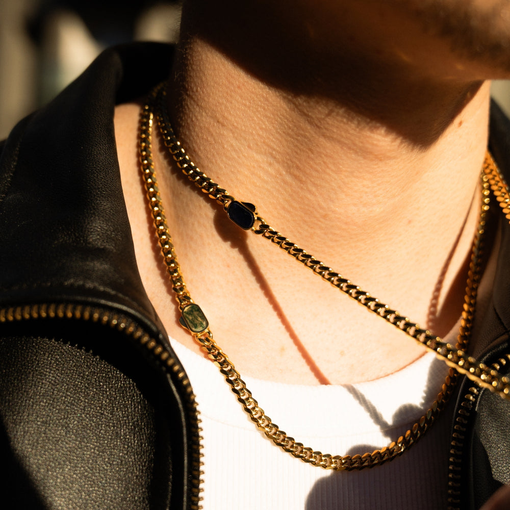 Close-up of a person wearing a gold chain necklace with a blurred background