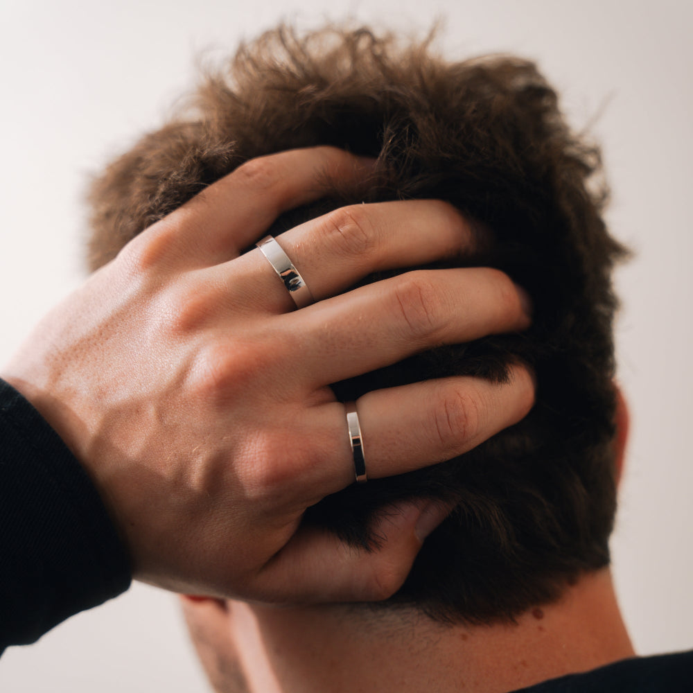 Person wearing two silver rings on fingers with a blurred background