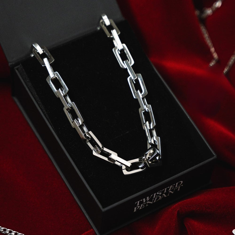 Silver chain necklace on a black display card with 'Twisted Pendant' text, against a red fabric background.