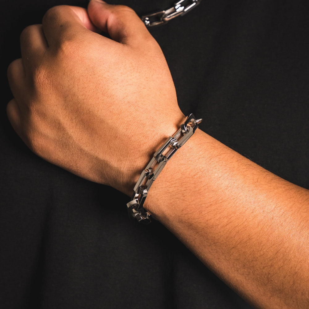 Hand wearing a silver chain bracelet on a dark background