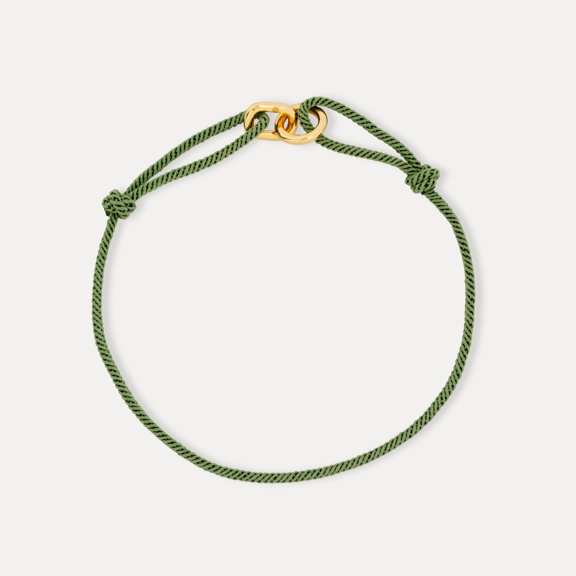 Green braided bracelet with a gold clasp on a light gray background