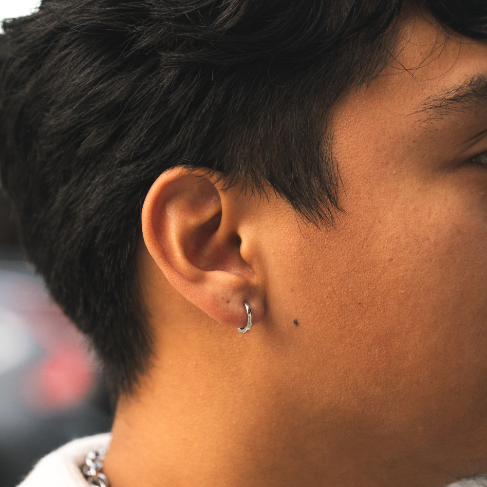 Close-up of a person's ear with a hoop earring against a blurred background