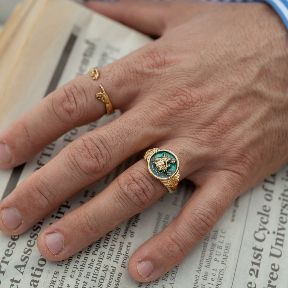 Hand wearing a gold ring with a blue gemstone on a newspaper background