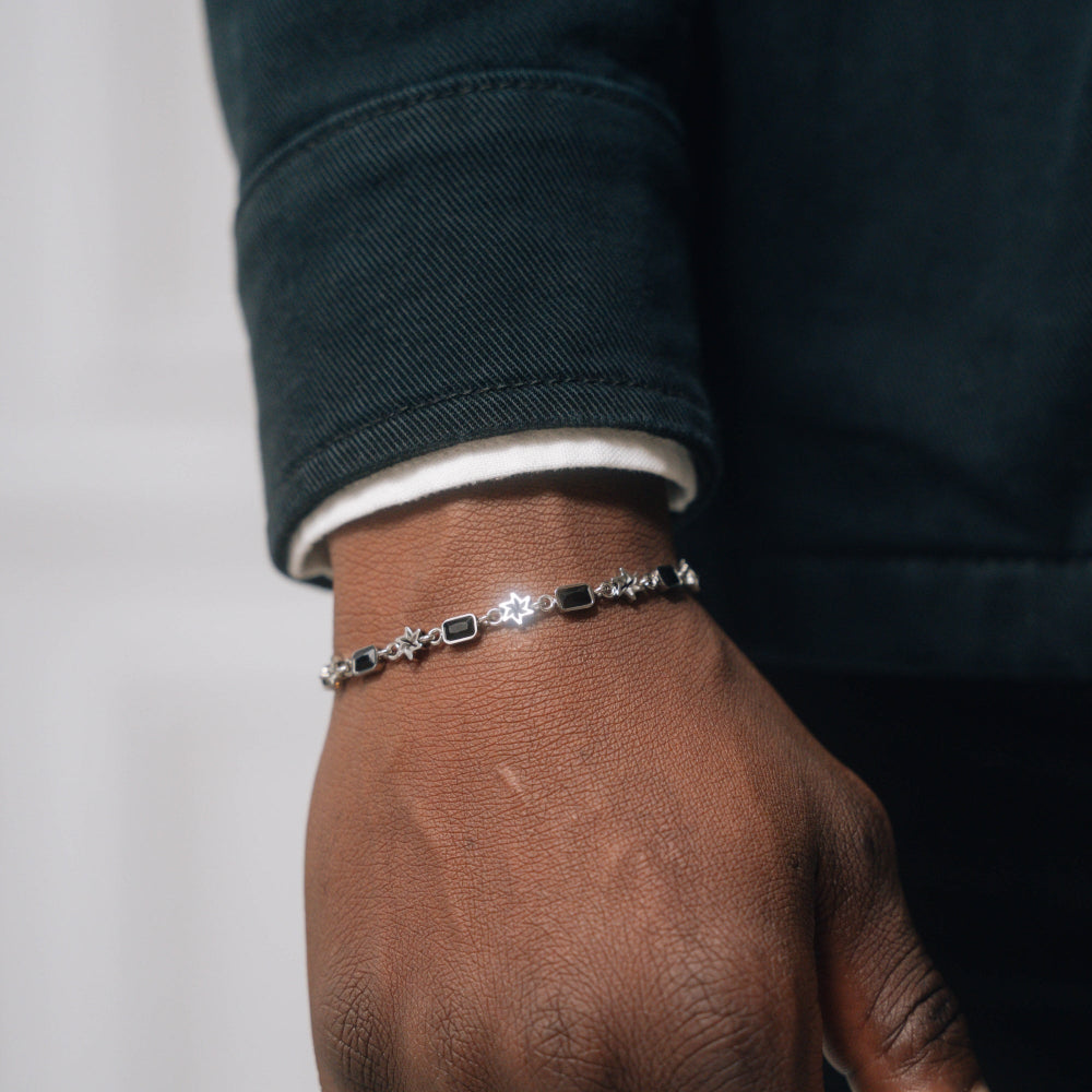 Silver bracelet on a wrist with a neutral background