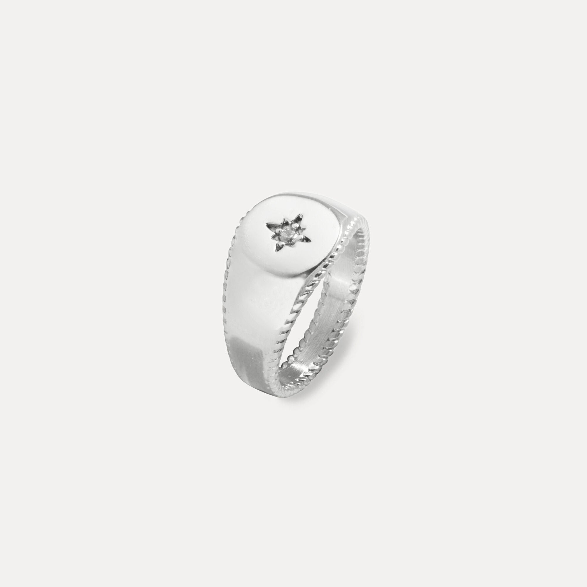 Silver ring with a diamond on a light gray background