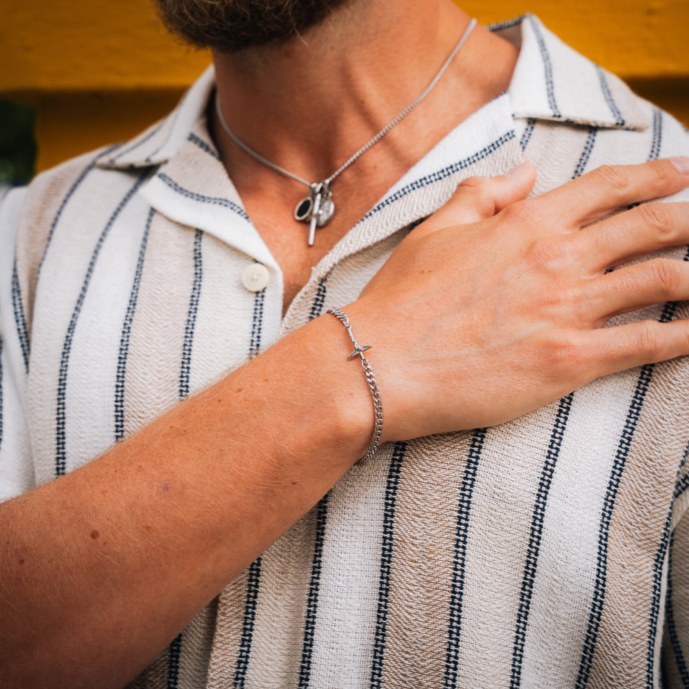 Person wearing a necklace and bracelet with a striped shirt