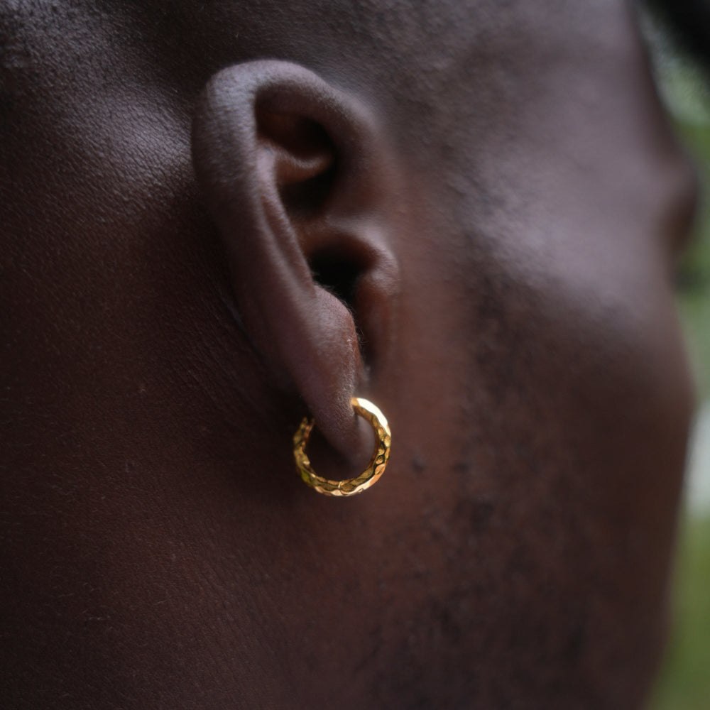 Close-up of a person wearing a gold hoop earring.