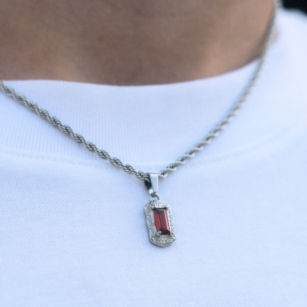 Necklace with a pendant featuring a red gemstone on a white shirt