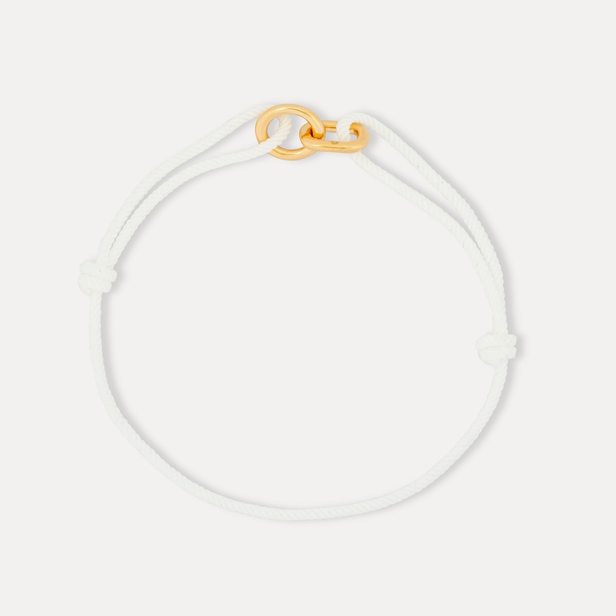 White bracelet with a gold clasp on a light gray background