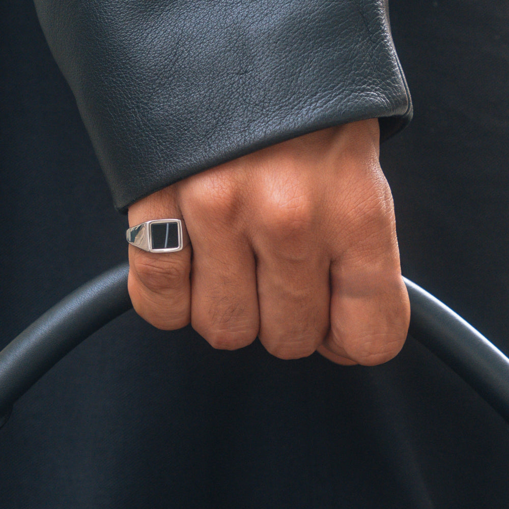 Hand wearing a ring with a dark background