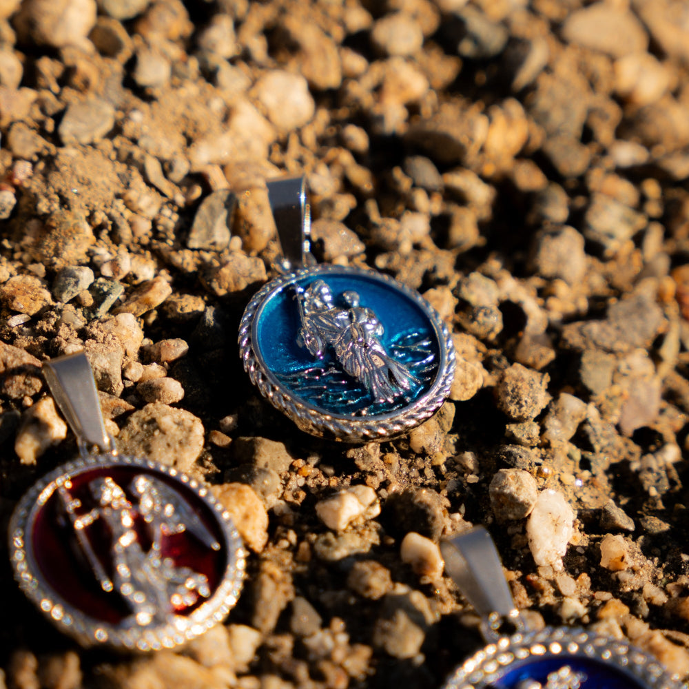 Three silver pendants with enameled designs on a textured surface