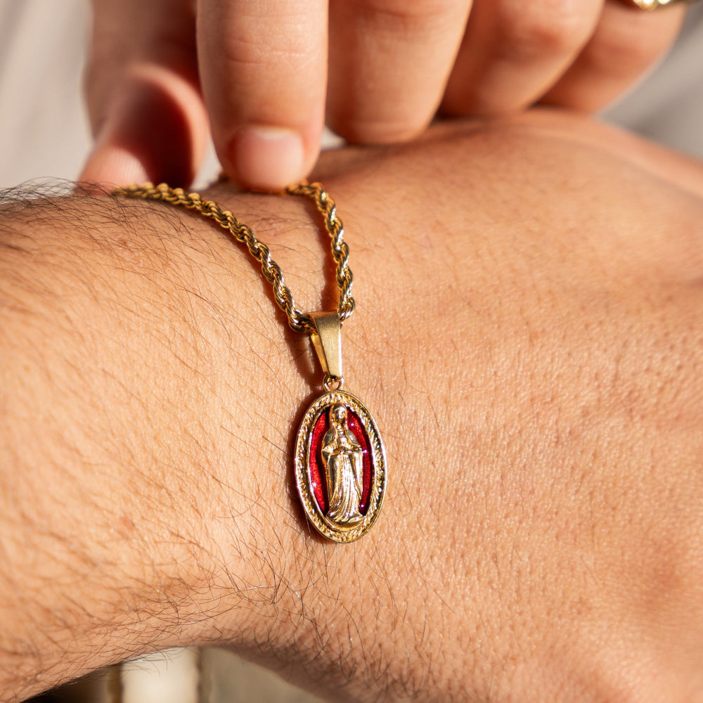 Gold chain with a red pendant on a wrist