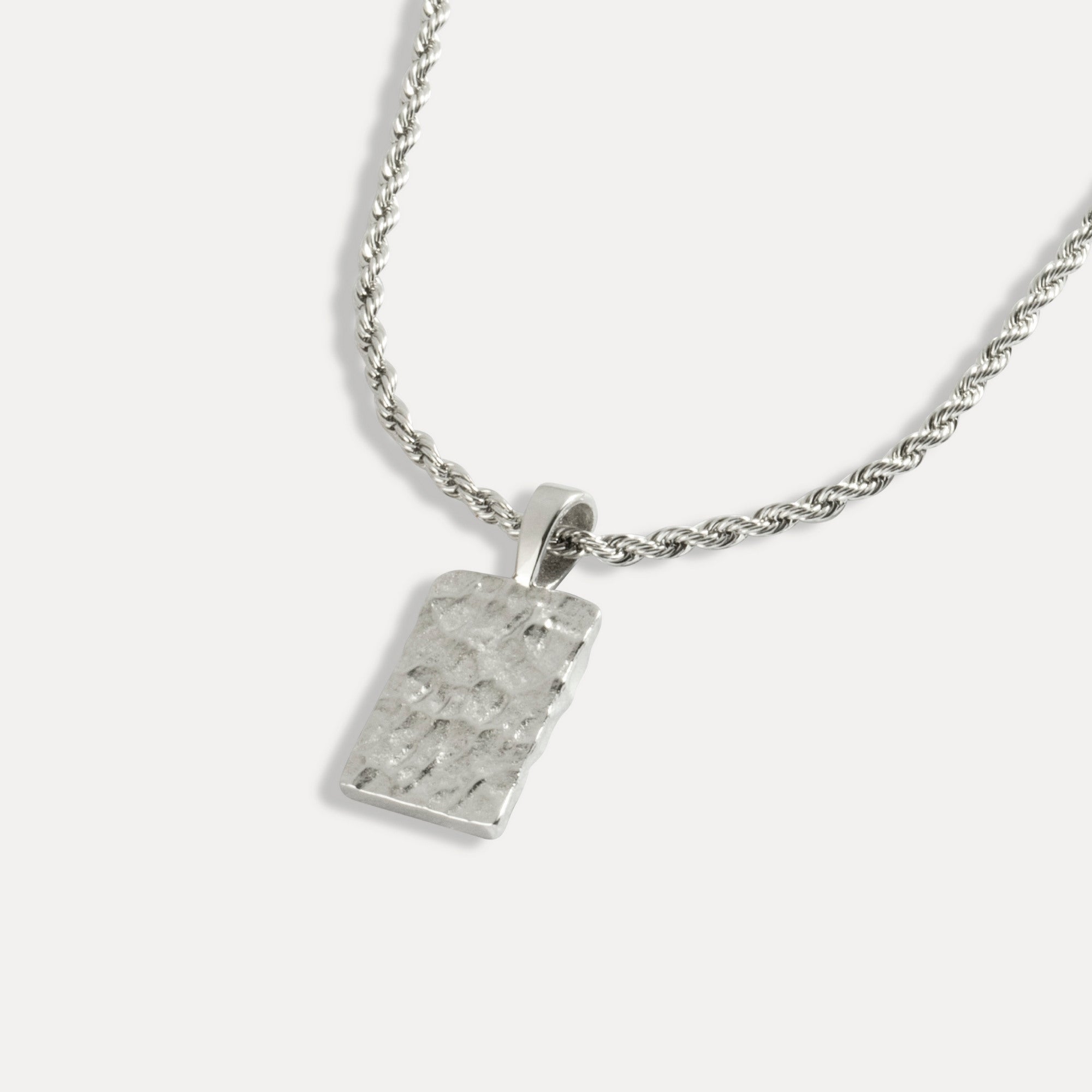 A silver rectangle hammered pendant attached to a silver rope chain necklace.