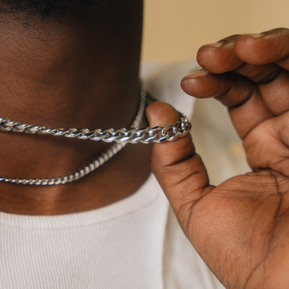 Person wearing a silver chain necklace with a blurred background