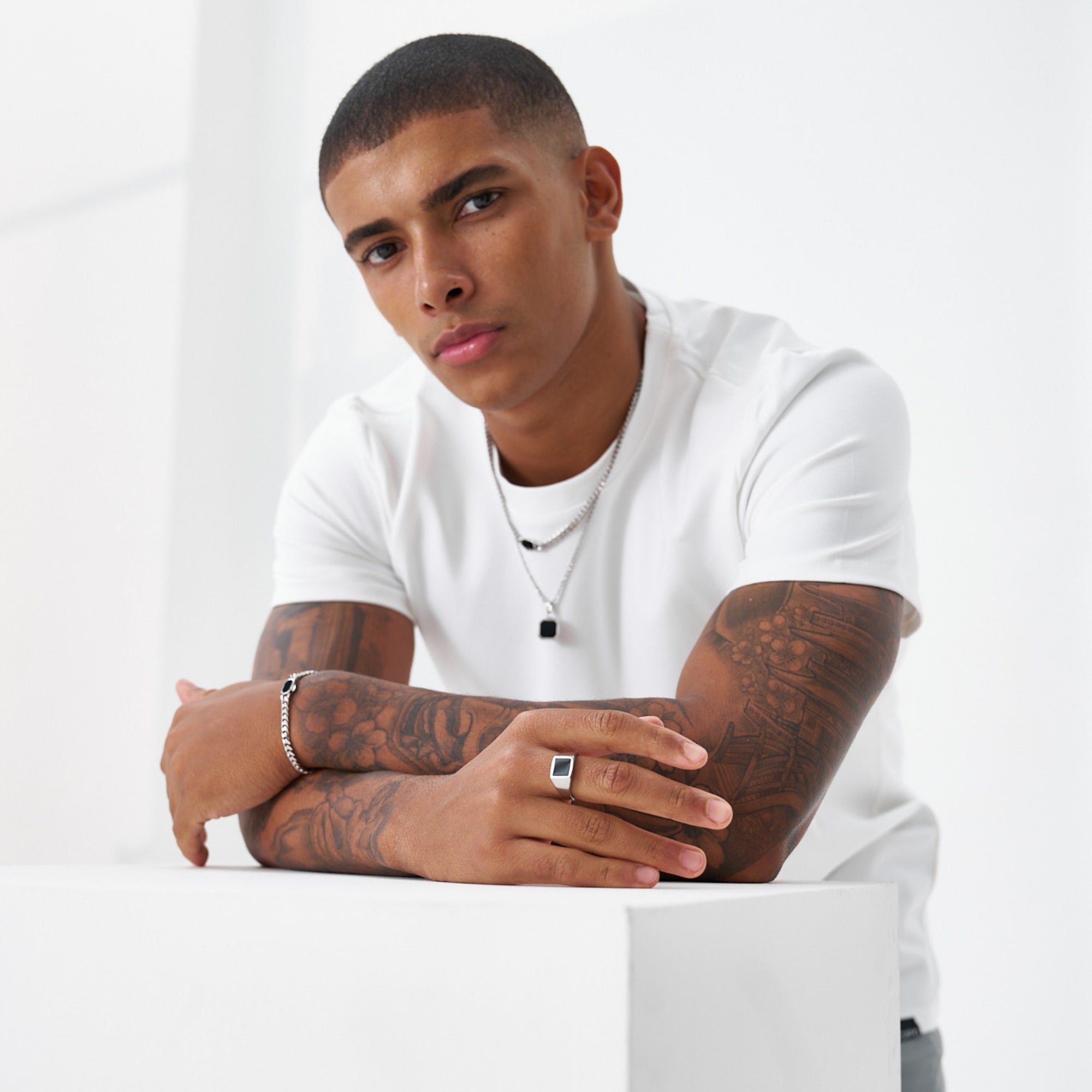 Man with tattoos wearing a white t-shirt on a white background