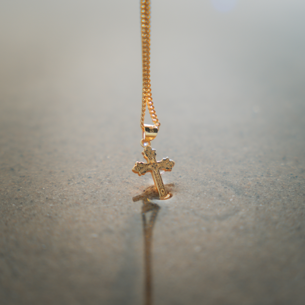 Gold cross necklace on a gray surface