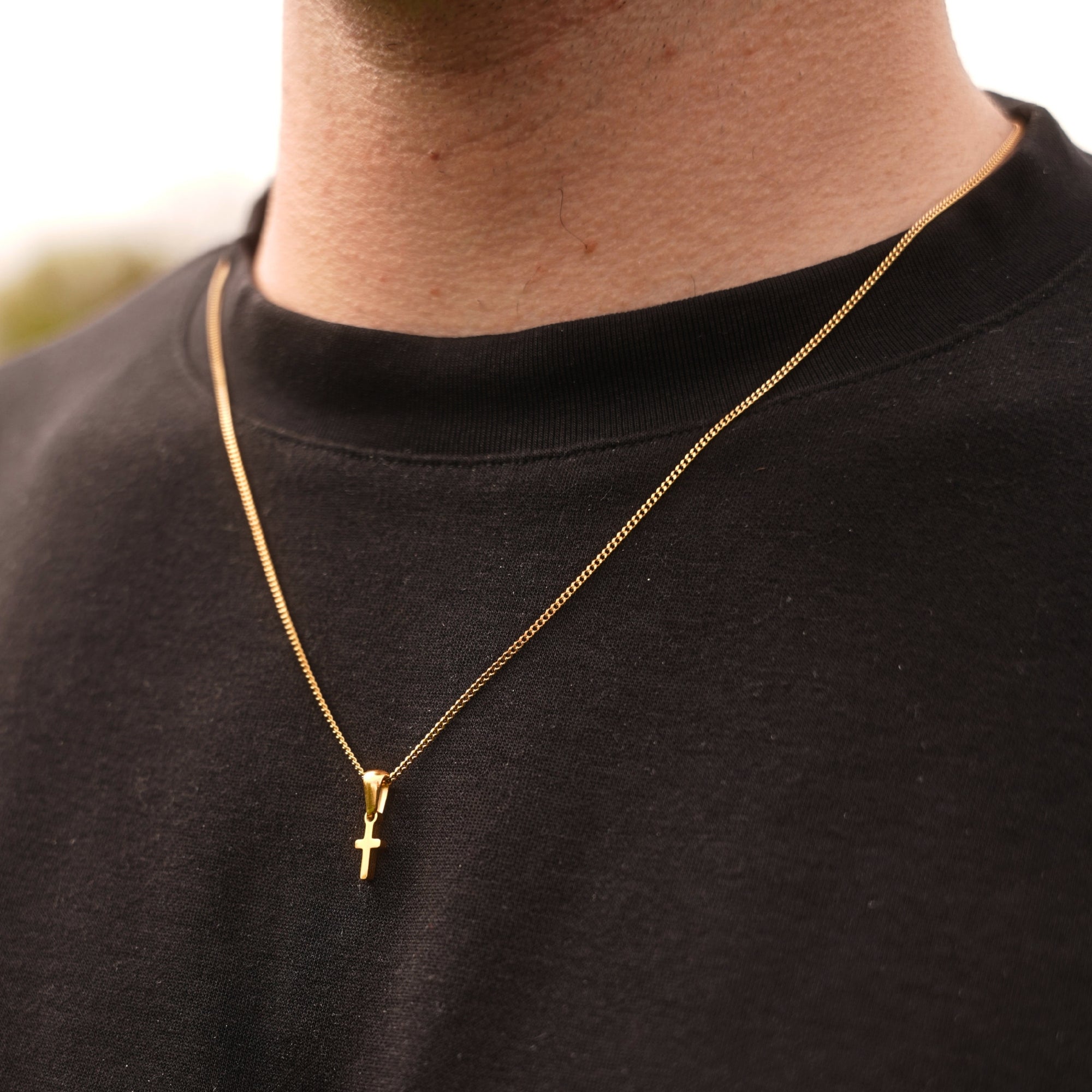 Gold necklace with a cross pendant on a black shirt