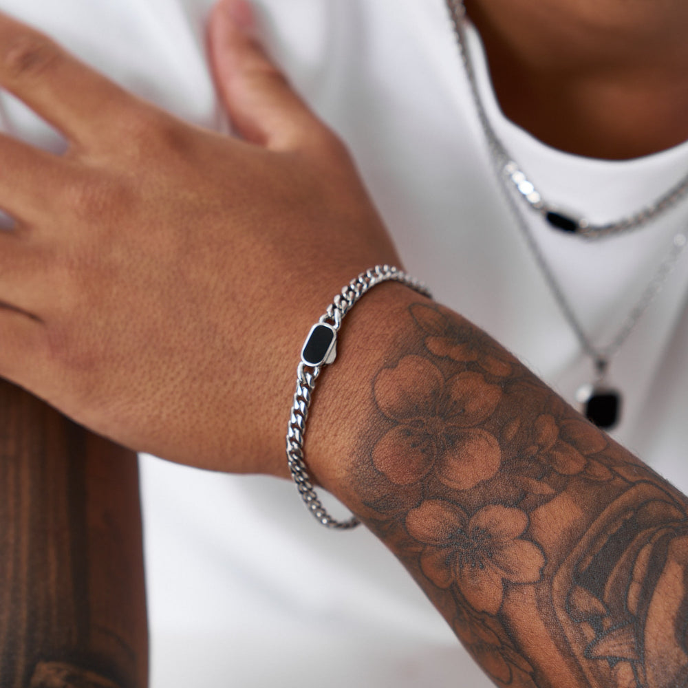 Person wearing a silver chain bracelet on a white background